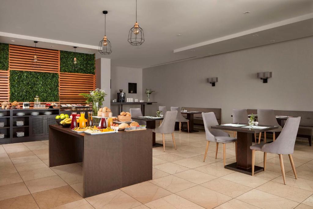 a restaurant with tables and chairs and a kitchen at NH Tenerife in Santa Cruz de Tenerife