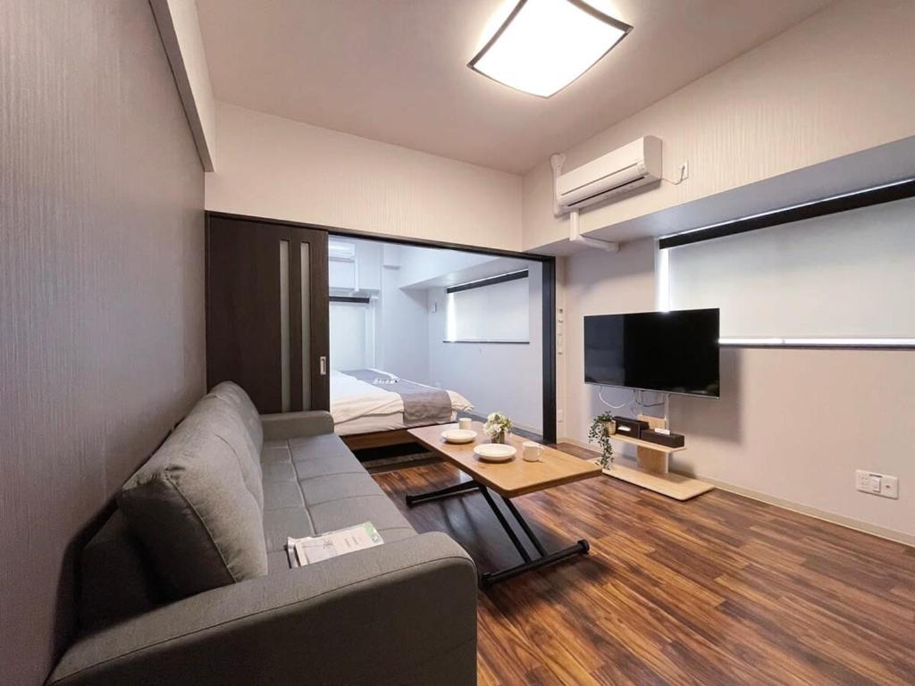 a living room with a couch and a tv at bHOTEL Casaen - Brand New 1BR Apt Near Hondori Shopping District For 6 Ppl in Hiroshima