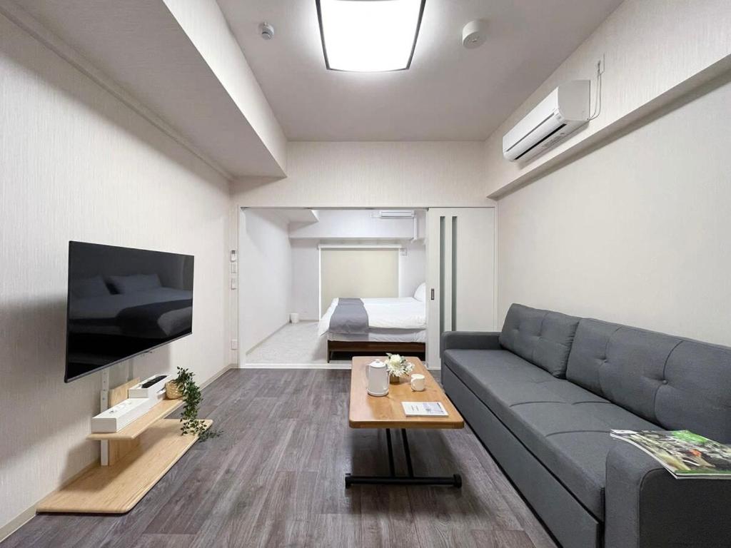 uma sala de estar com um sofá e uma televisão em bHOTEL Casaen - Spacious 1BR Apt For 6 Ppl Great Location with room wifi em Hiroshima