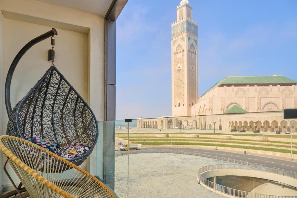 wiklinowe krzesło przed budynkiem z wieżą zegarową w obiekcie Apartment Sea View B9 - Mosquée Hassan II - By TheCasaEdition w mieście Casablanca