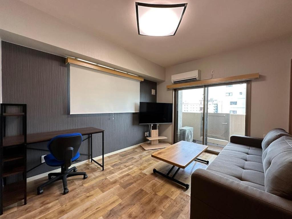 広島市にあるCasaen - New 1Br Apt few minutes walk to Hondori Districtのソファとテーブルとスクリーンのあるリビングルーム