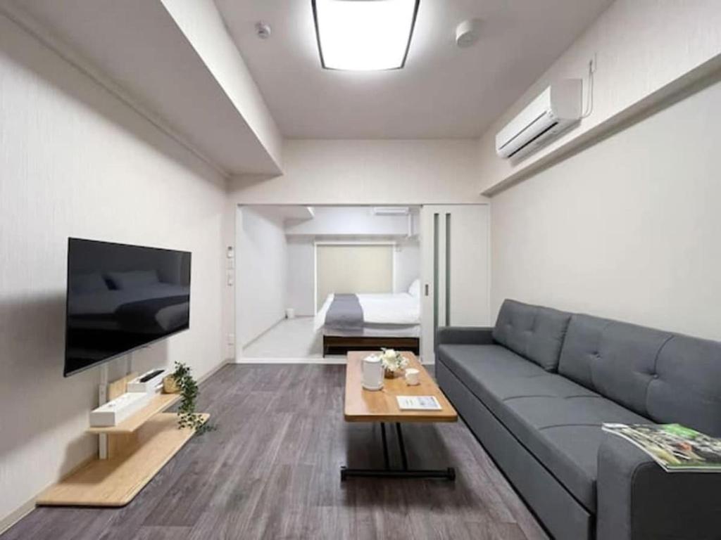 Una sala de estar con un sofá y un televisor en Casaen by b hotel- Modern 1 BR near Hondori District for 6 Ppl, en Hiroshima