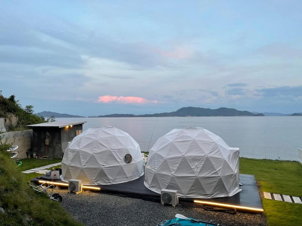 dos cúpulas blancas en un remolque junto a un cuerpo de agua en bLOCAL Sugawa House - 2 BR Beach Front House for 8 Ppl en Kure