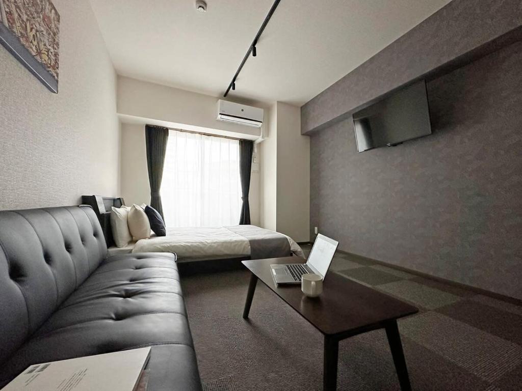 広島市にあるbHOTEL Nagomi - Well-Furnished with balcony Apt for 3 Pplのリビングルーム(ソファ、ノートパソコン、テーブル付)