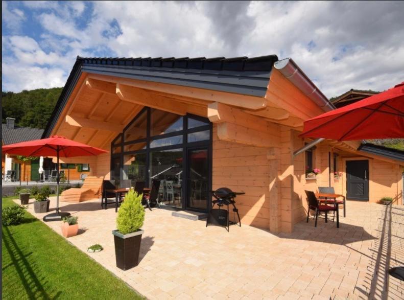 a wooden house with a patio with chairs and umbrellas at Blockhaus Edelweiss in Rieden