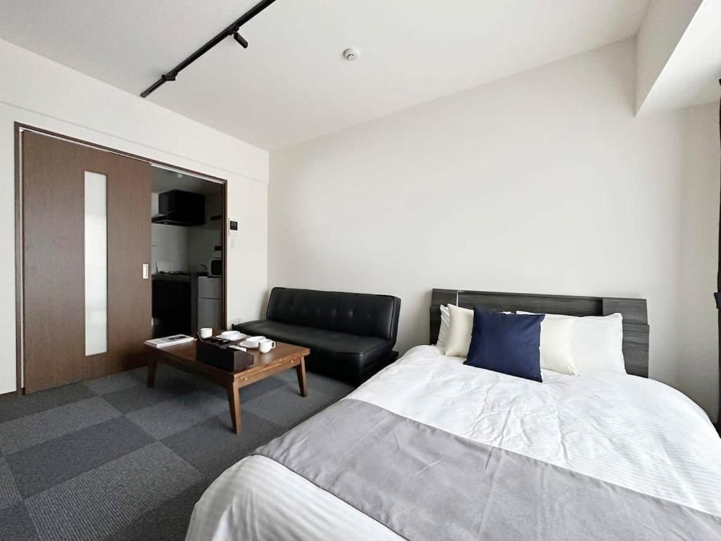 廣島的住宿－bHOTEL Nagomi - Comfy 1 Bedroom in City Center for 3ppl，一间卧室配有一张床和一张沙发