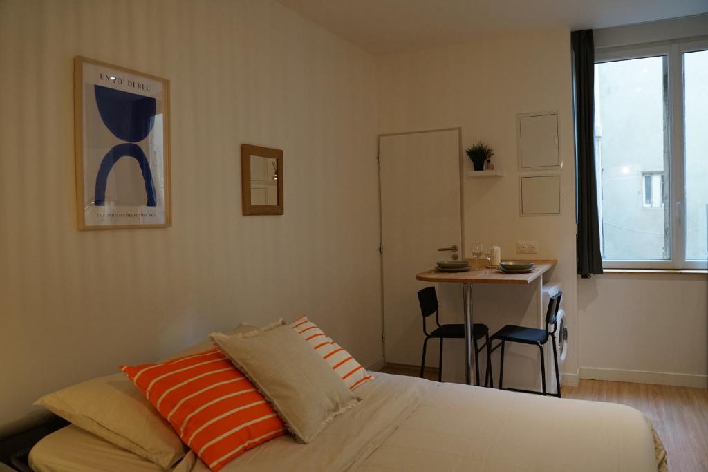 a bedroom with a bed and a table in it at Studio cosy Eglise Notre-Dame-des-Calades in Villefranche-sur-Saône
