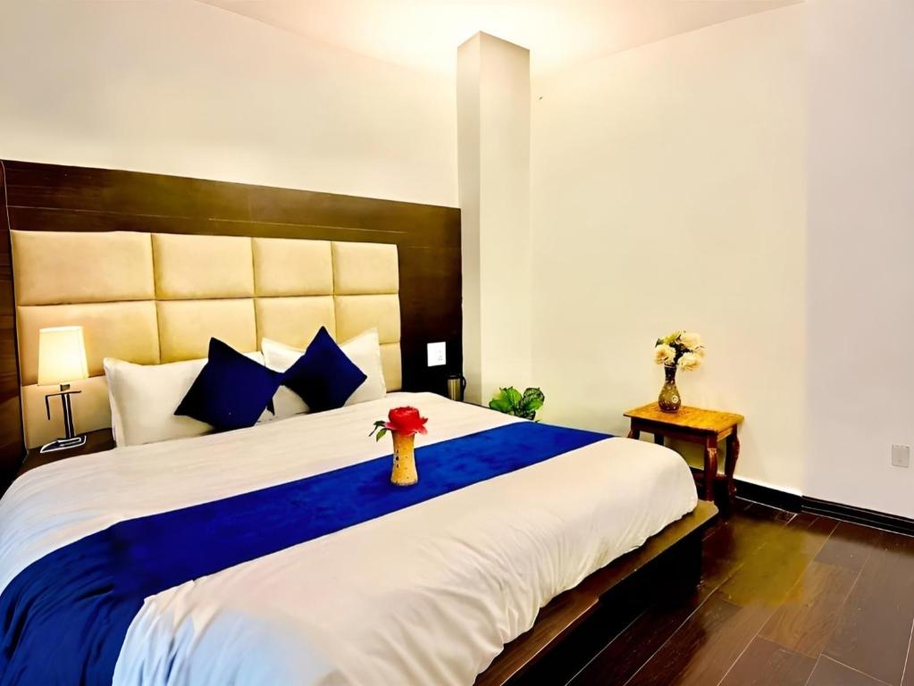 een slaapkamer met een groot bed en een blauwe deken bij The NDVL Hotel - Top Rated and Most Awarded Property in Haridwar in Haridwār
