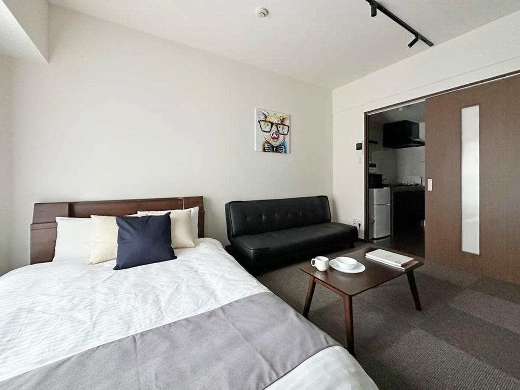 a bedroom with a bed and a couch and a table at bHOTEL Nagomi - Stylish 1 BR Apt near City Centre for 3Ppl in Hiroshima