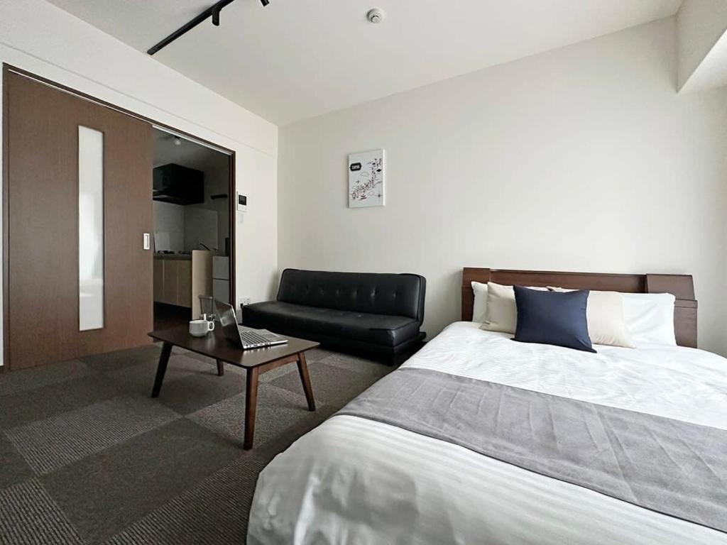 広島市にあるbHOTEL Nagomi - 1 Bedroom Apt in City Centre w balcony for 3 Pplのベッドルーム1室(ベッド1台、ソファ、テーブル付)