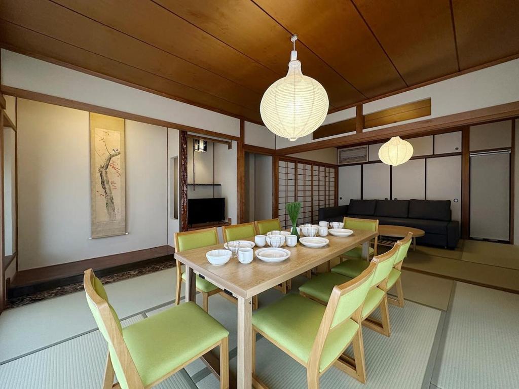 bLOCAL Itsuki - Charming Private House in Miyajimaguchi Near Itsukushima Shrine Upto 18 ppl في هاتسوكايتشي: غرفة طعام مع طاولة وكراسي خشبية