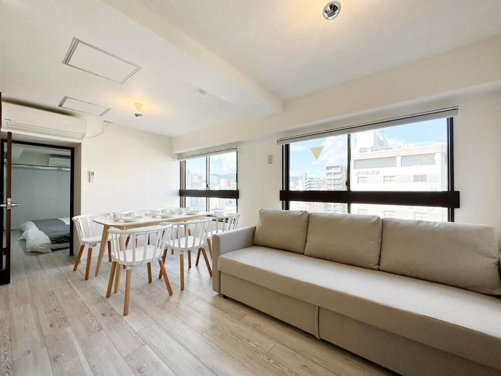 a living room with a couch and a table with chairs at Mitao bld - Beautiful Apt for 10Ppl Very Near to Peace Park in Kami-nagarekawachō