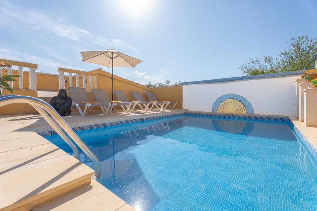 a swimming pool with chairs and an umbrella at Casa Rosa in Torrent