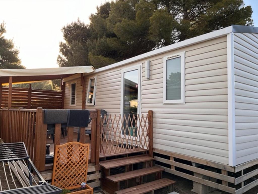 una casa pequeña con porche y terraza en Mobil home Clim, Tv - Camping Falaise Narbonne Plage 4 étoiles - 004, en Narbonne-Plage