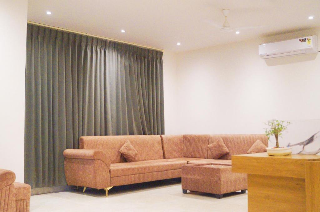 a living room with a brown couch and green curtains at Hotel The Shan Exotica in Bhopal
