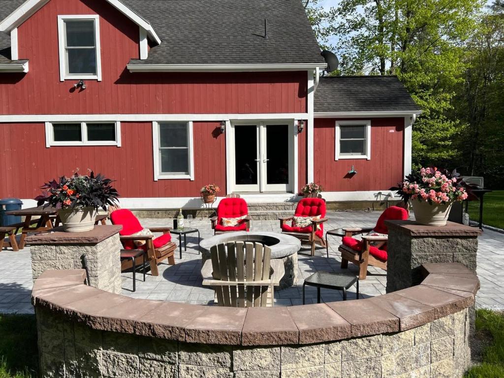 a red house with a patio with chairs and a table at Berkshire Vacation Rentals: Peaceful Post and Beam Loft Sleeps 9 in New Marlborough