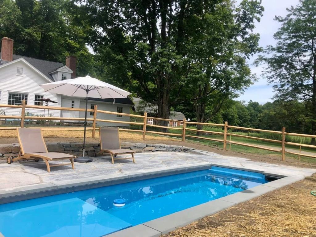 einen Pool mit 2 Stühlen und einem Sonnenschirm in der Unterkunft Berkshire Vacation Rentals: Private Estate Heated YEARROUND Outdoor Pool in North Egremont