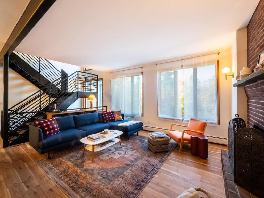 ein Wohnzimmer mit einem blauen Sofa und einer Treppe in der Unterkunft Private Berkshires Home On 5+ Acres Rustic & Chic in Otis