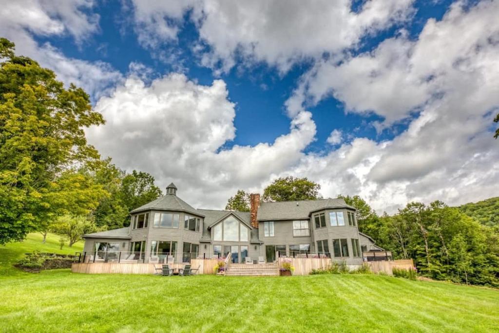 a large house with a large grassy yard at Berkshire Vacation Rentals: The Brookman: Renovated 6000 SF Estate On 40 Acres in Williamstown