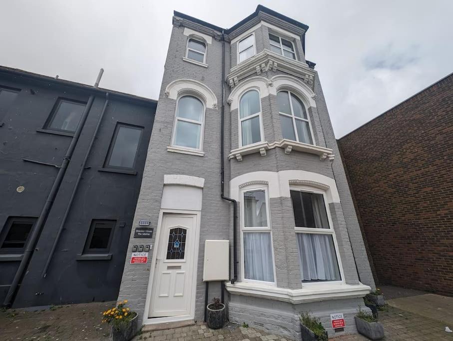a tall brick building with a white door at Seaview House - Flat 2 in Lowestoft