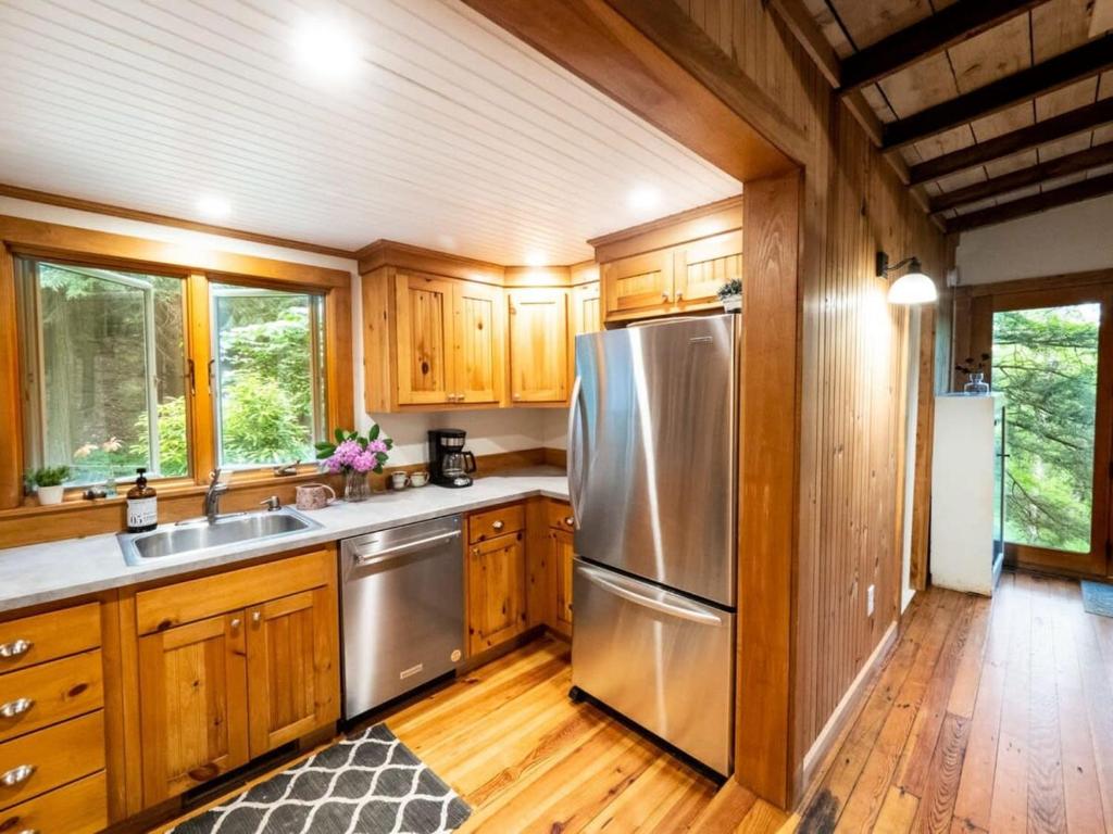 una cocina con nevera de acero inoxidable y armarios de madera en Berkshire Vacation Rentals: Private Cottage Come Enjoy Nature, en Canaan