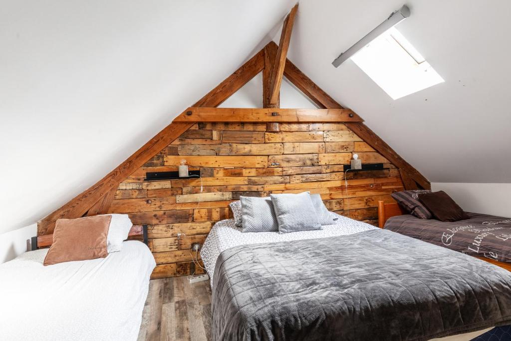a attic bedroom with two beds and a wooden wall at Espaces Gîtes in Sainte-Escobille