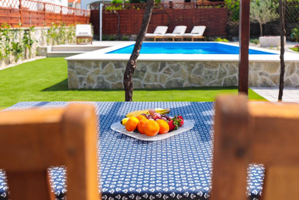 a plate of fruit on a table next to a pool at Home Away From Home with a heated pool in Punat