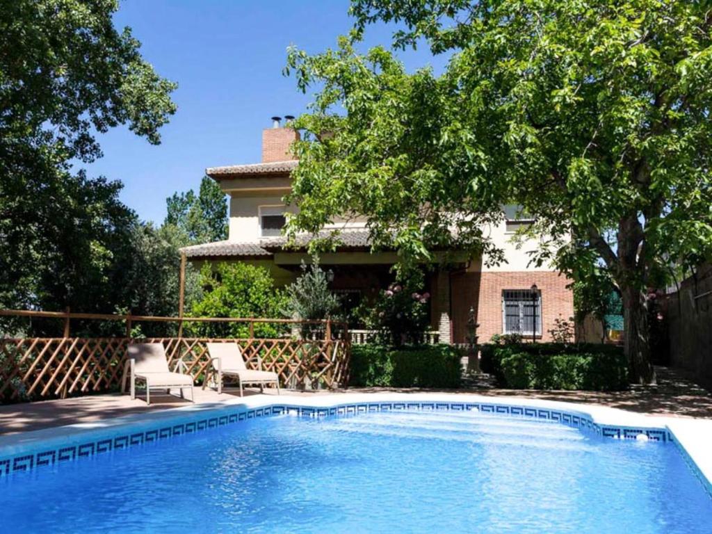 una piscina con 2 sillas y una casa en Casa rosa del romeral, en Nigüelas
