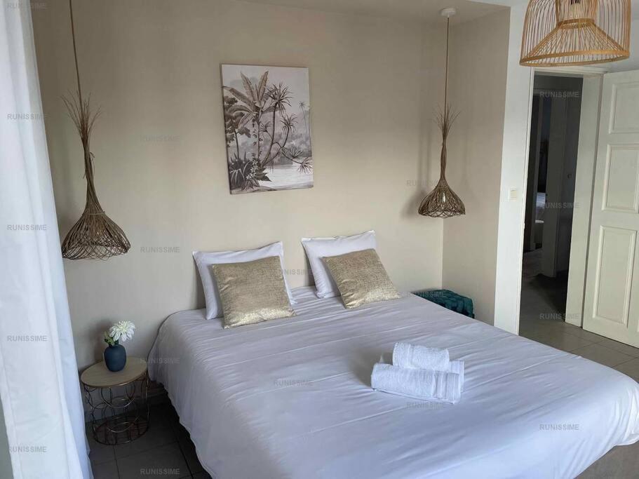 a large white bed with pillows in a bedroom at Ocean-Villa 12 personnes avec piscine à 50m de la plage de l'Etang Salé Les Bains in Étang-Salé les Bains