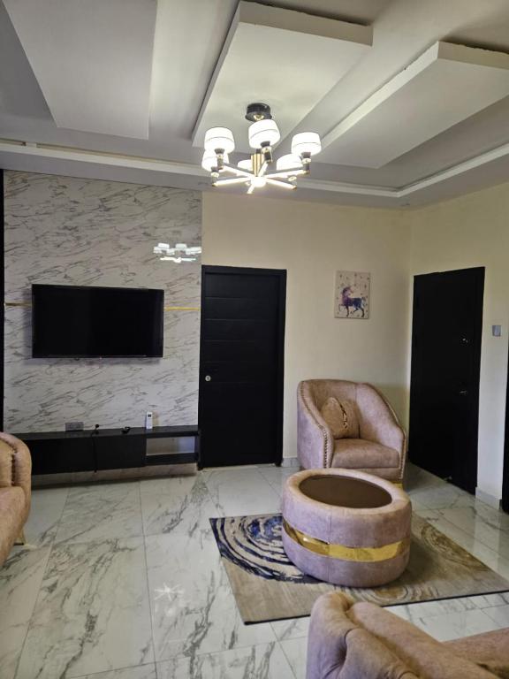 a living room with two chairs and a flat screen tv at MDCUBE HOMES AND PROPERTIES in Ibadan