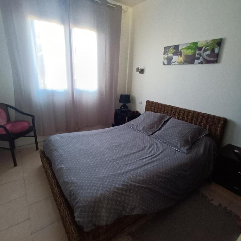 une chambre avec un lit, une chaise et une fenêtre dans l'établissement Maison bord de mer, à Penta-di-Casinca