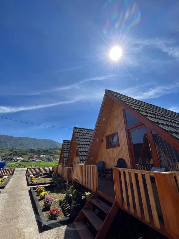 a cabin with a deck with the sun in the sky at DIENG COTTAGE 2 in Dieng