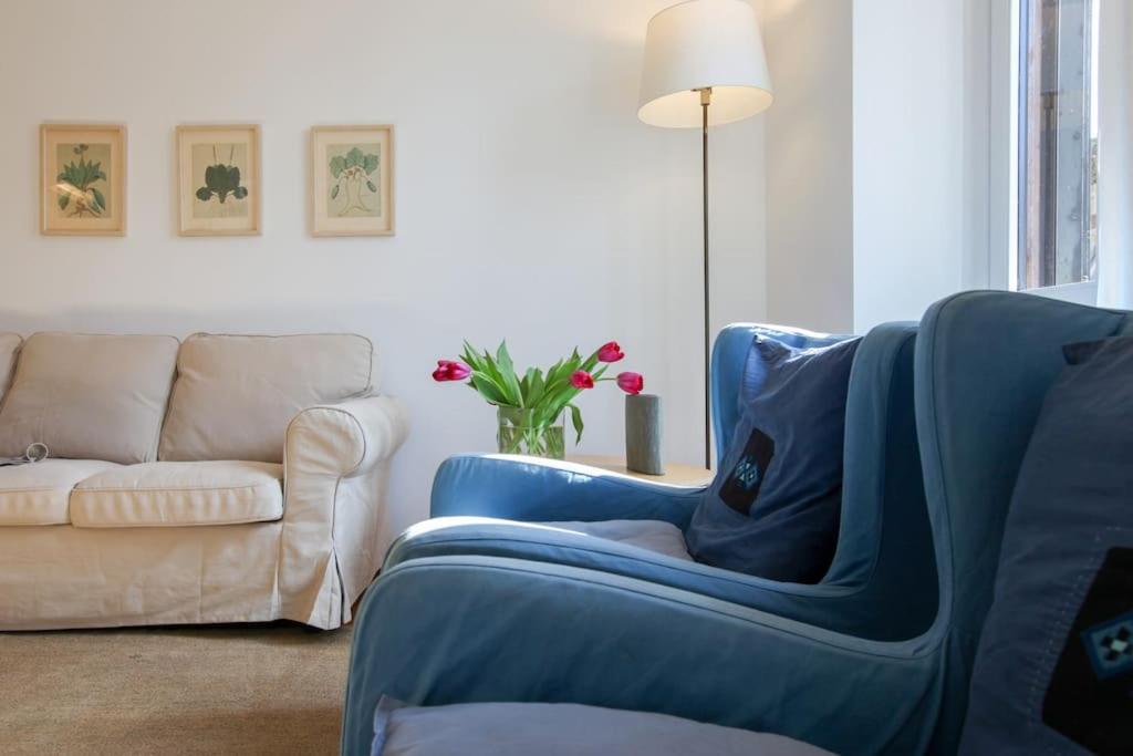 a living room with a blue chair and a couch at HACCA Collection - Brera & Fashion District - Bright 2BR Apt in Milan