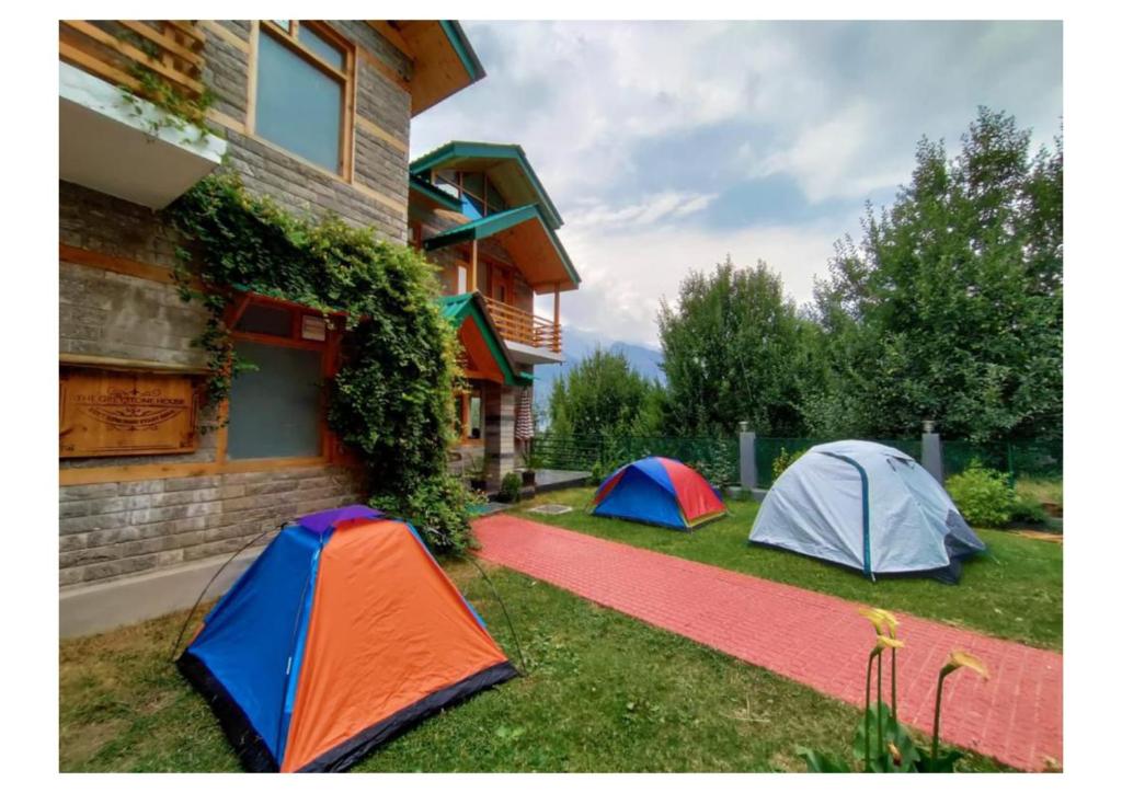 three tents on the grass next to a house at Western Hill in Manāli