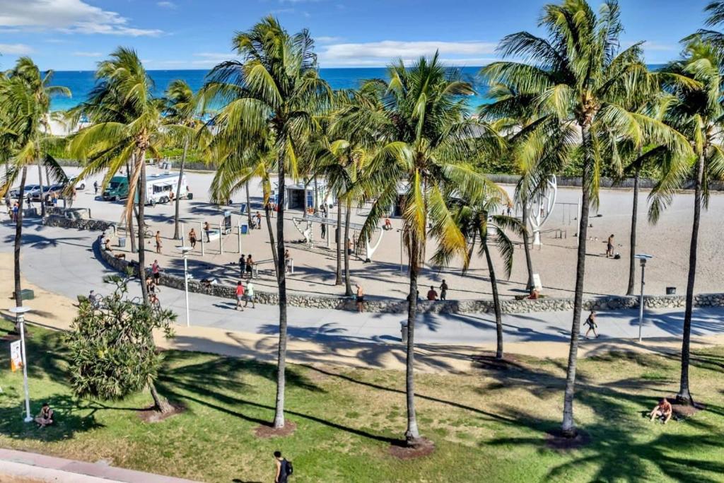 people walking on a beach with palm trees at NEW Amazing large 3BR direct oceanfront Penthouse On Ocean Drive!! in Miami Beach