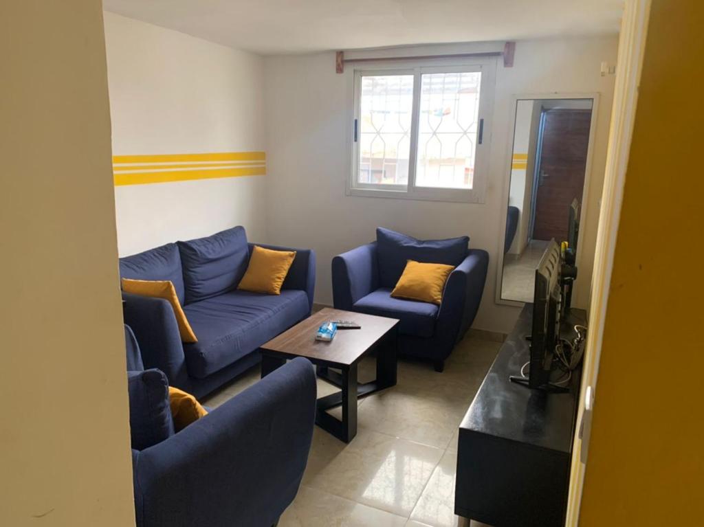 - un salon avec des canapés bleus et une table dans l'établissement Résidence l'endroit, à Abidjan