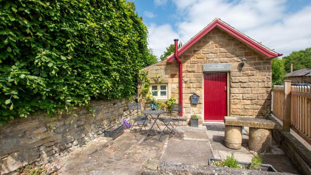 Ce cottage en pierre dispose d'une porte rouge et d'une table. dans l'établissement The Old Weighbridge, à Bakewell