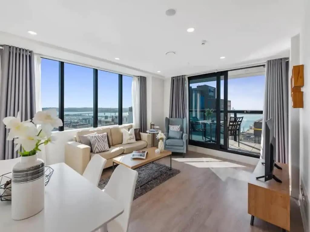 a living room with white furniture and large windows at Just Opposite to Sky tower , 2 Bed 2 Bath in CBD in Auckland