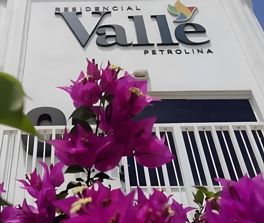 Casa condomínio fechado. في بترولينا: حفنة من الزهور الأرجوانية أمام المبنى