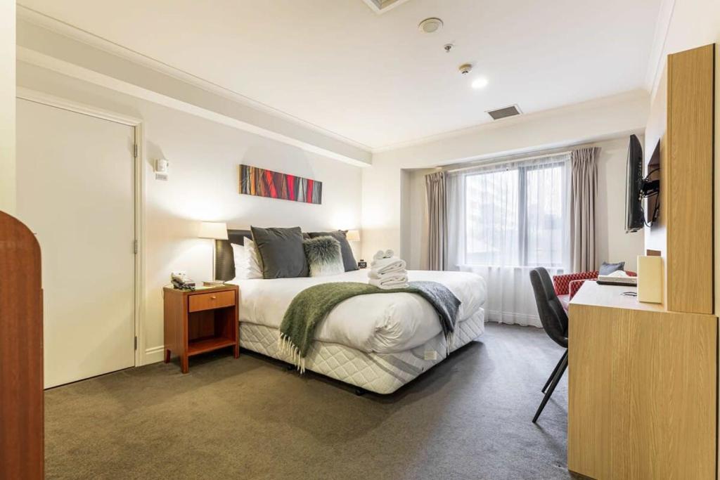 a white bedroom with a bed and a window at Lovely studio room in Citylife Hotel in Auckland