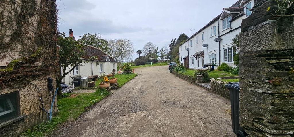 a dirt road in a village with white houses at Davy Cottage in Menheniot