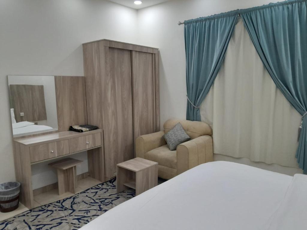 a bedroom with a bed and a chair and a mirror at دار الكيان للشقق المخدومة - Dar Al Kayan Serviced Apartments in Jeddah