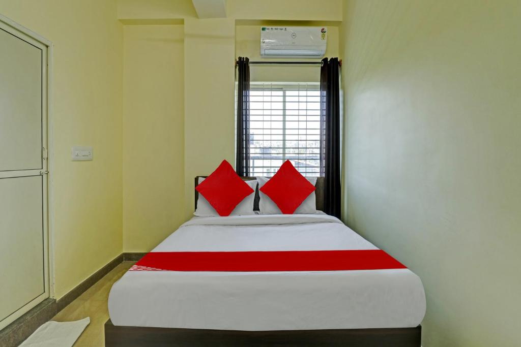OYO Flagship Sri Chamundeshwari Boarding And Lodge في بانغالور: سرير في غرفة عليها وسائد حمراء