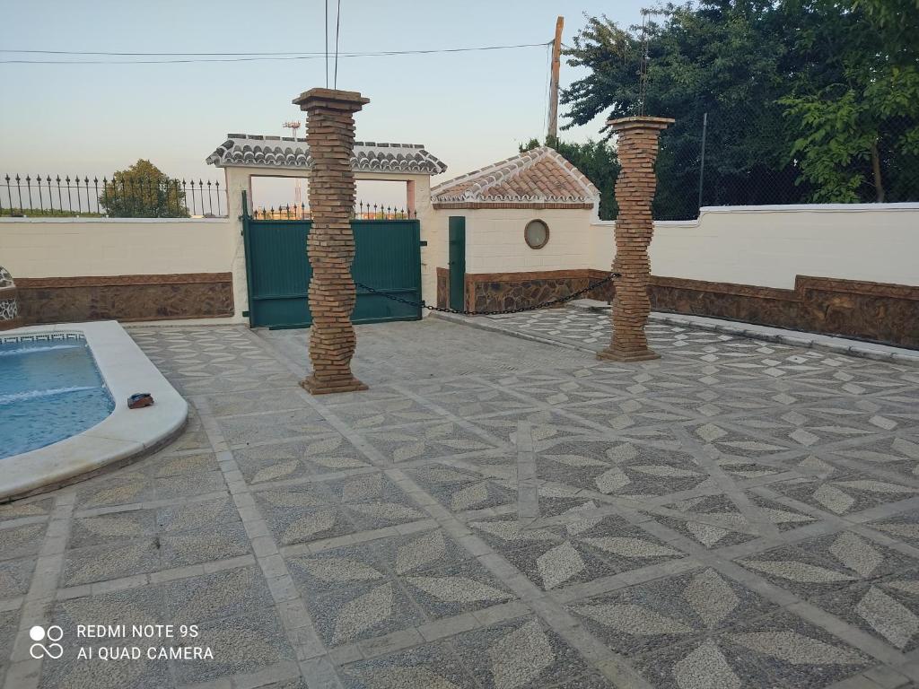 eine Terrasse mit zwei Säulen und einem Pool in der Unterkunft Casa rural pilas in Pilas