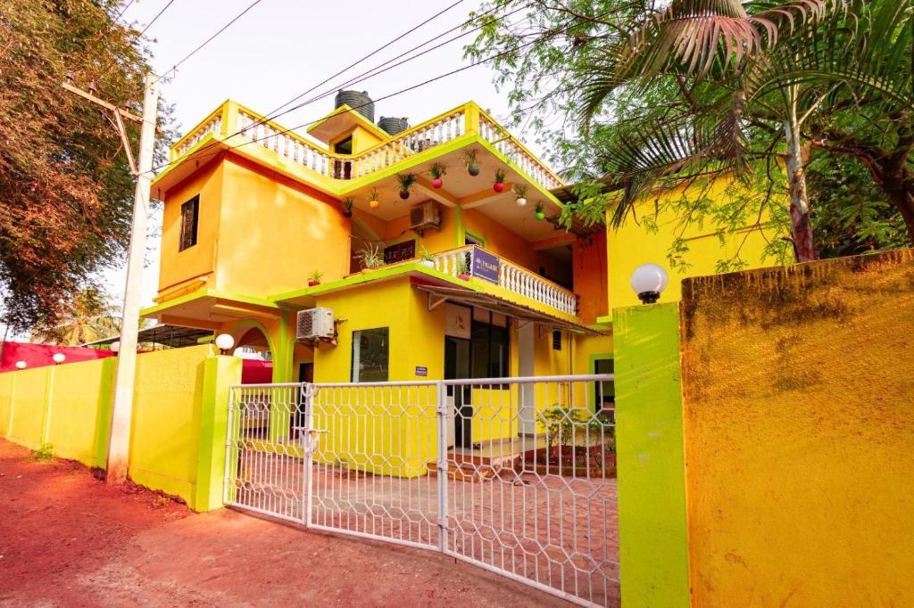 a yellow house with a fence in front of it at Palash Villa in Aguada