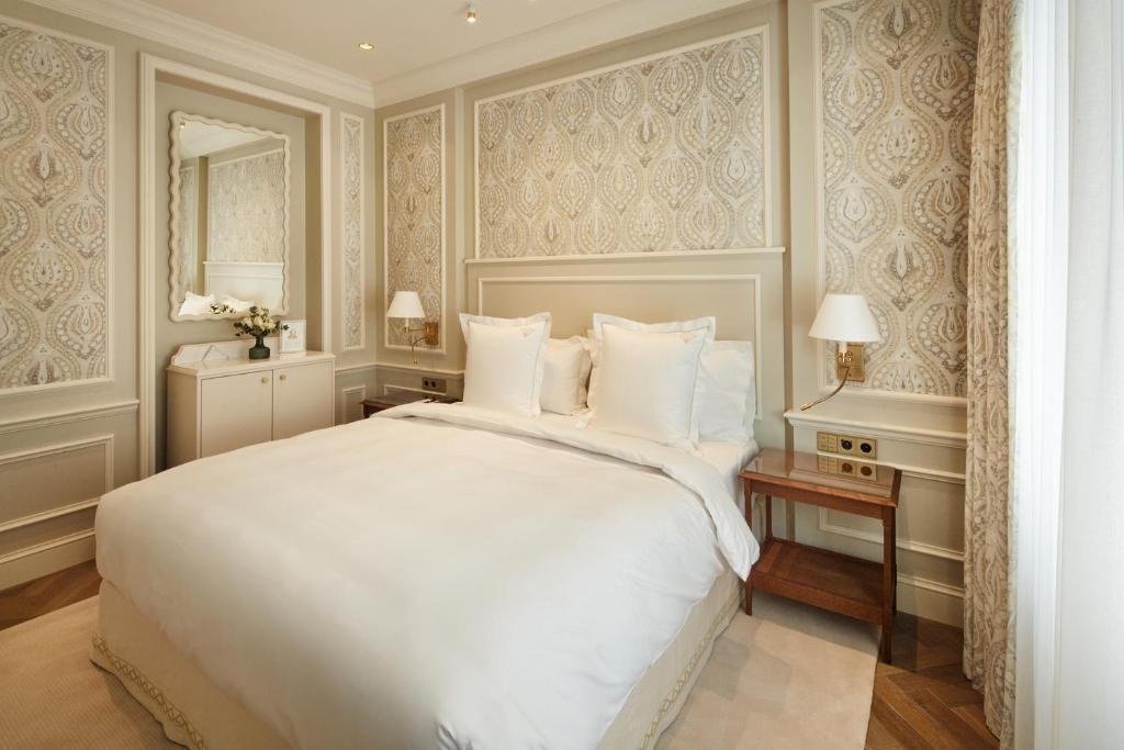 a bedroom with a large white bed and a mirror at Hotel Zur Wiener Staatsoper in Vienna