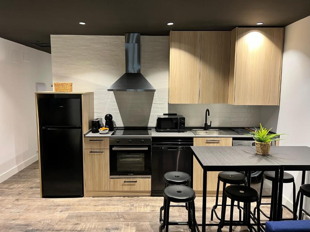 eine Küche mit einem schwarzen Kühlschrank und einem Tisch in der Unterkunft Apartamenticos El Tubo I in Saragossa