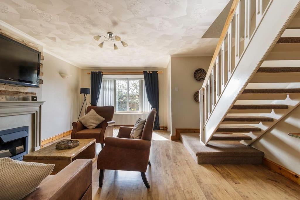 un soggiorno con scala, divano e sedie di Modest 3 Bed Home, Normanton a Normanton