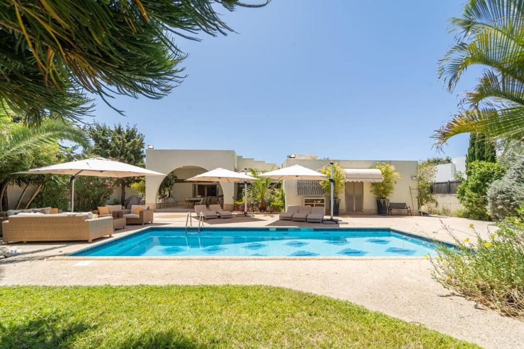 - une piscine avec des chaises et des parasols dans une cour dans l'établissement Luxury Villa 5 BDR Pool In Caesarea, à Césarée