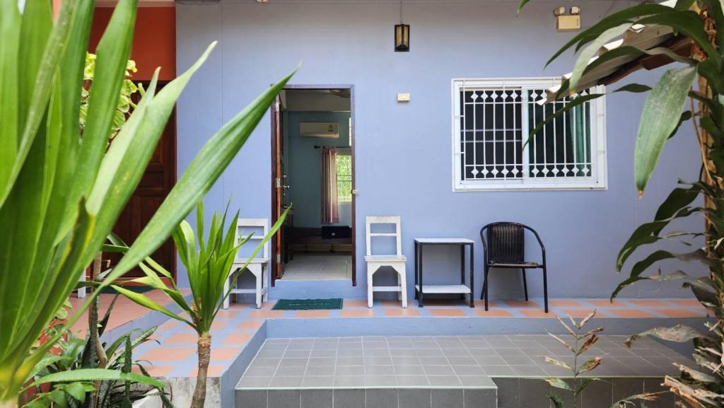 a house with a blue wall and chairs in the courtyard at Sarin Guesthouse สาริน in Koh Tao